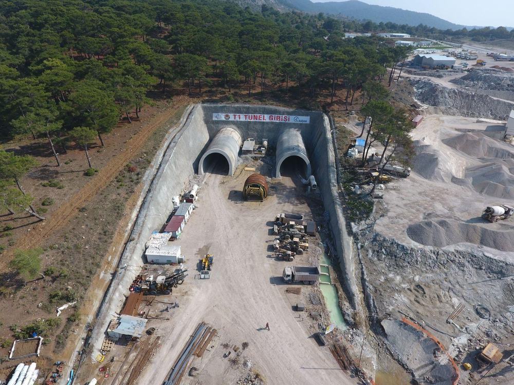 Twin tunnel portals under construction at the foot of a hillside