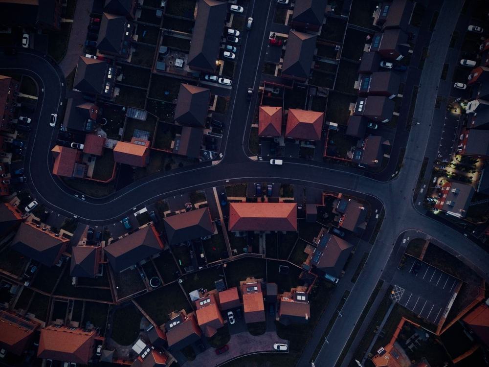 A suburban neighbourhood at dusk, its streets picked out by lighting
