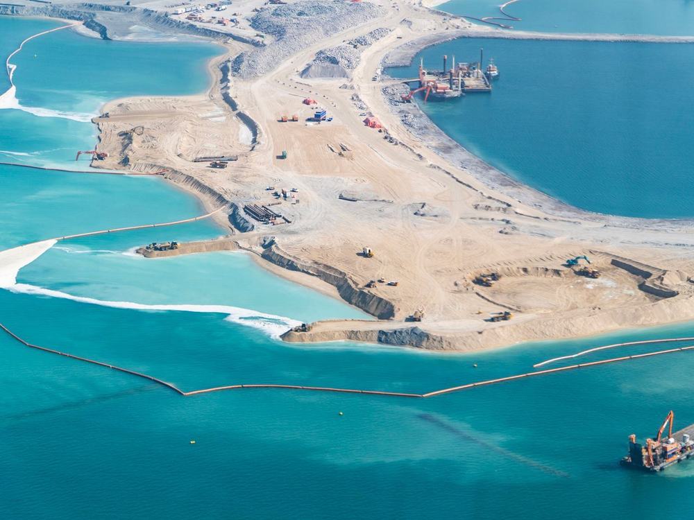 Newly reclaimed land pushing out into shallow turquoise water