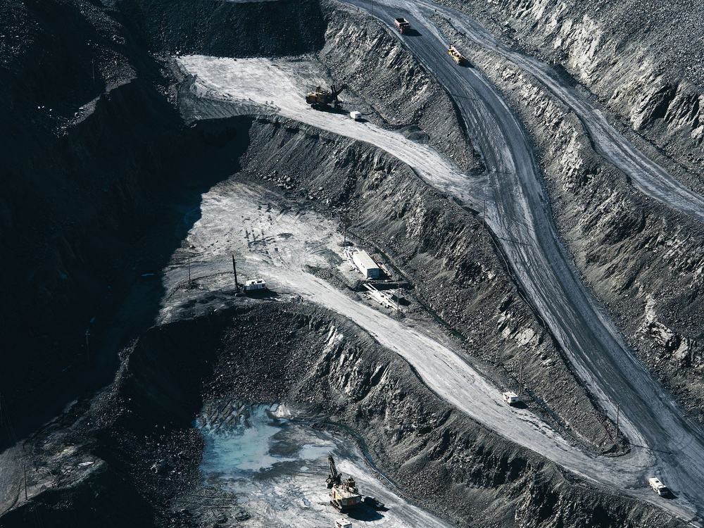 Aerial view of mine workings, haul roads cutting between dark spoil