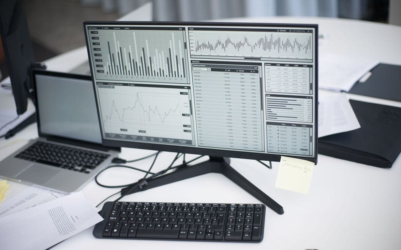 A desk monitor showing charts and a table of figures